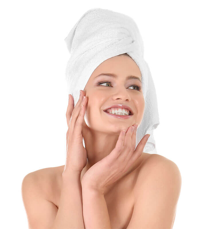 smiling woman after shower with towel wrapped on her head admiring her skin